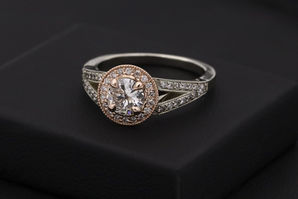 A halo diamond engagement ring resting on a dark box