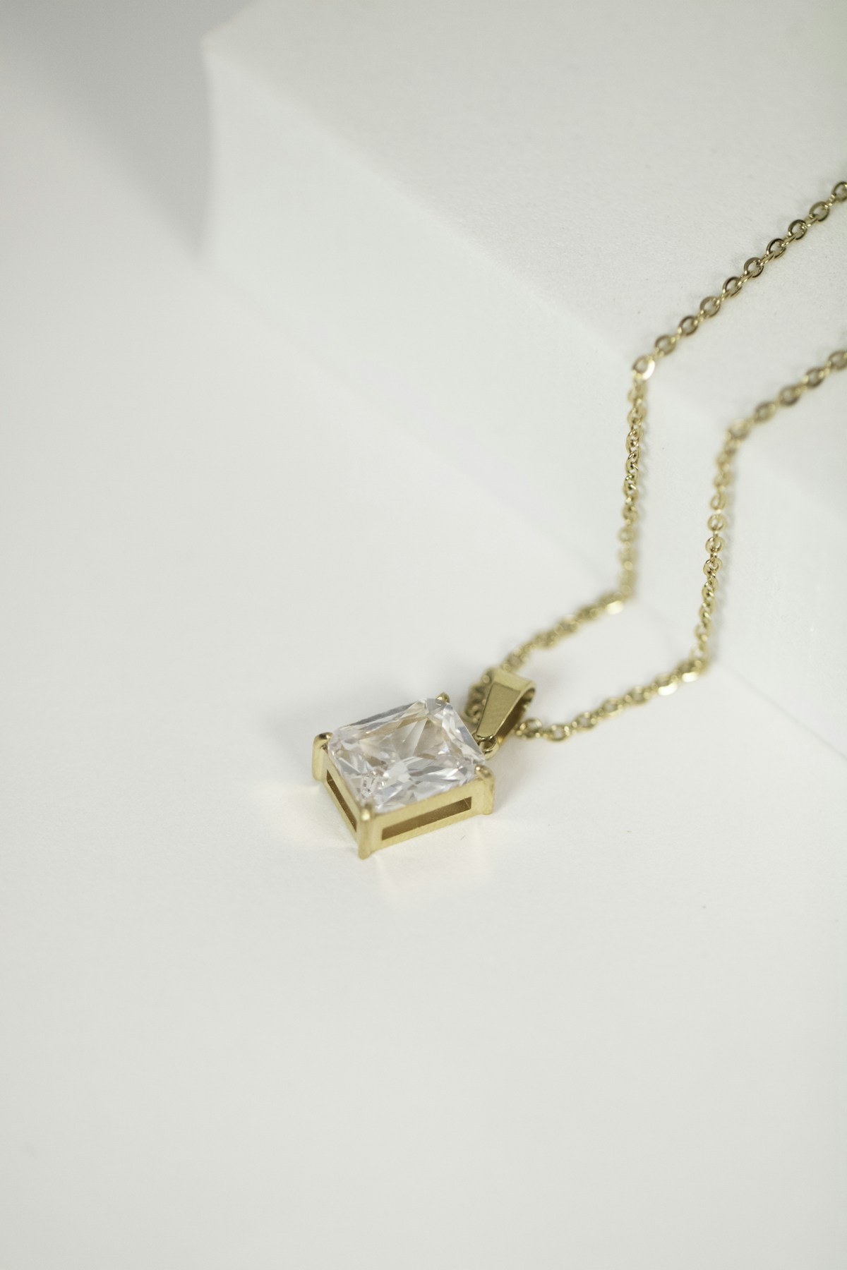 A square diamond pendant on a delicate gold chain