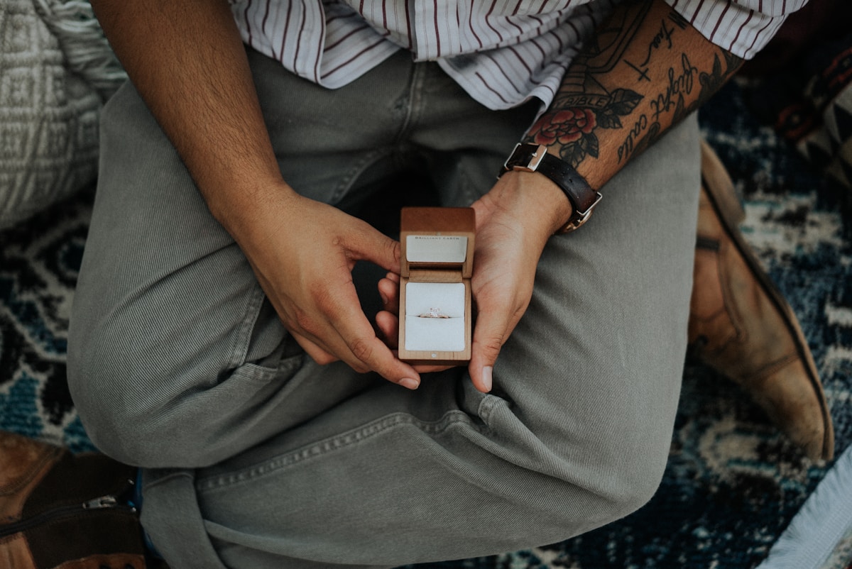 A man holding an open ring box before a proposal
