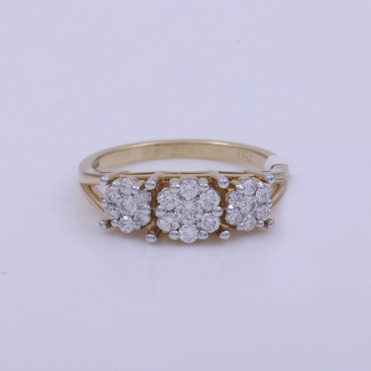 A gold three-stone diamond cluster ring on a white background