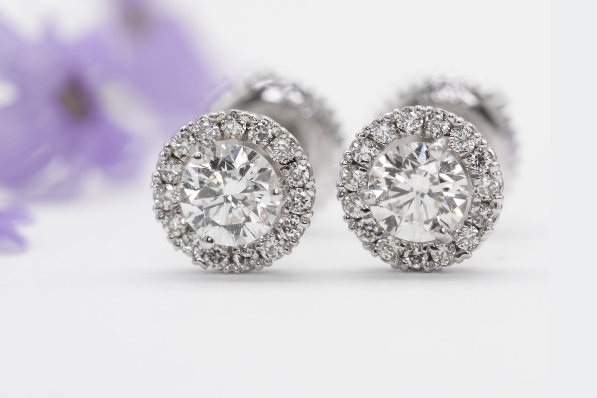 Diamond halo stud earrings sparkling on a white surface